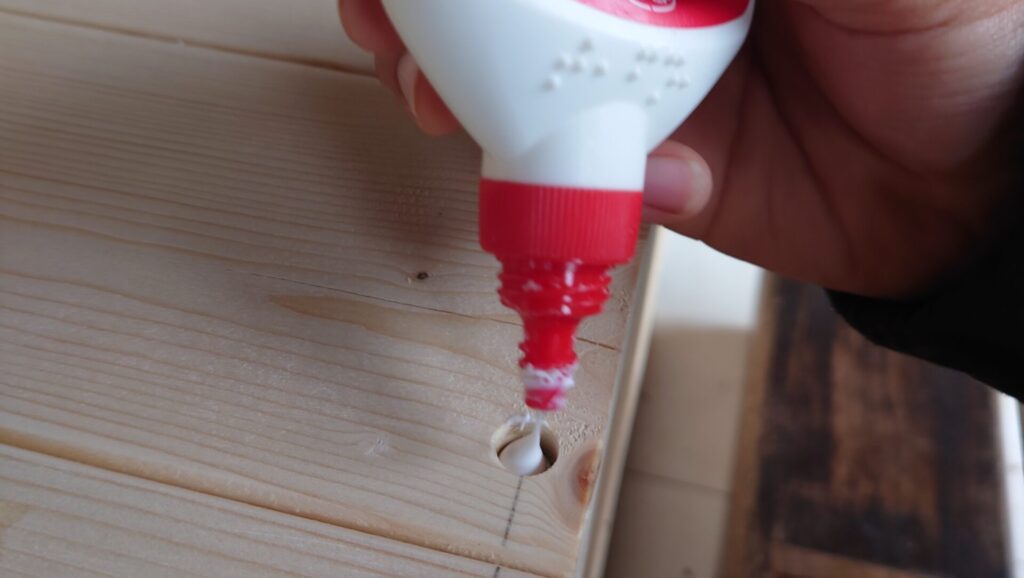 木材にあけた穴に木工用ボンドを入れる様子。